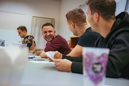 The team sitting at a table in a meeting room, laughing CEO in the middle